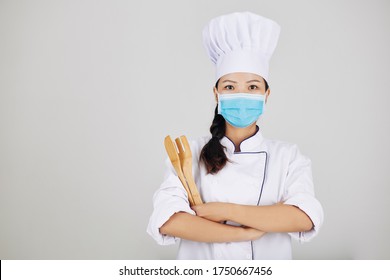 Confident Young Restaurant Chef In Medical Mask Posing With Wooden Utensils