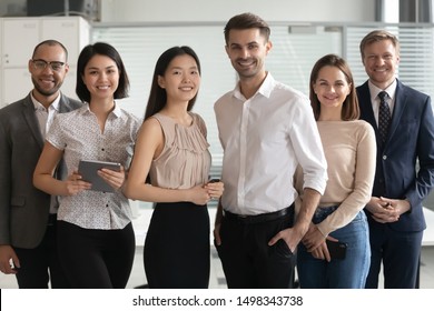 Confident Young Smiling Diverse Professional Team Leaders Standing Together With Mixed Race Colleagues Portrait. Happy Group Of Multicultural Employees Posing Together With Skilled Mentors For Photo.