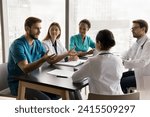 Confident young surgeon man in blue medic uniform talking to multiethnic colleagues in hospital meeting room, speaking to listening diverse doctors at table, offering ideas for clinic teamwork