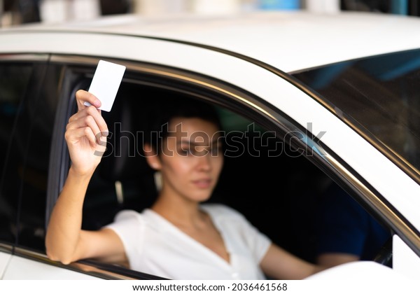 Confident young woman\
driver in car holding blank card mockup. Caucasian woman showing\
new driver\'s license 