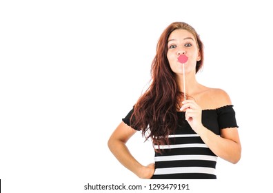 Confident Young Woman Holding A Photo Booth Prop In The Shape Of Red Lips Against A White Background