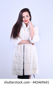 Confident Young Woman In Mink Coat. Smiling With Sly Look Standing In Studio