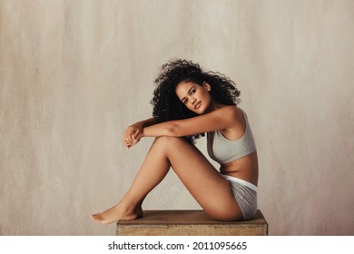 Confident Young Woman Posing In Her Natural Body. Body Positive Female Model Wearing Underwear And Looking At The Camera Against A Fabric Background.