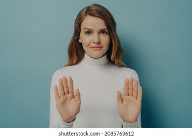 Confident Young Woman Showing Her Palms While Keeping Both Hands Outstretched In Stop Gesture Isolated Over Blue Studio Wall Background, Caucasian Female Saying No. Refusement Concept