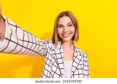 Confident young woman in stylish checkered jacket against yellow background, showcasing elegance and success in a casual professional look. - Powered by Shutterstock