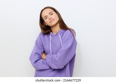confidently looking forward, a woman stands on a white background in a purple tracksuit with her arms crossed in front of her and her head tilted back