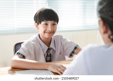 Confidently Smart Child In School Uniform Talking With A Teacher In Teacher's Room After Class. Preteen Boy Kid Doing Good On Interview Or Speaking Test At School. Teen Education Concept.