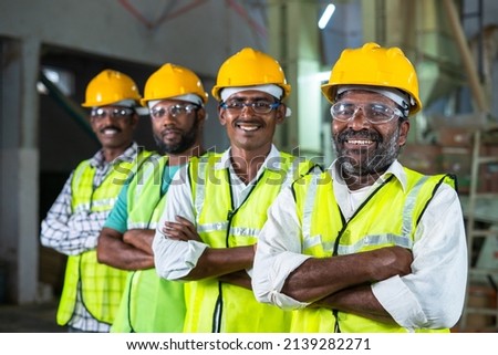 Confidently standing industrial workers with arms crossed by looking at camera - concept of workforce, occupation and safety
