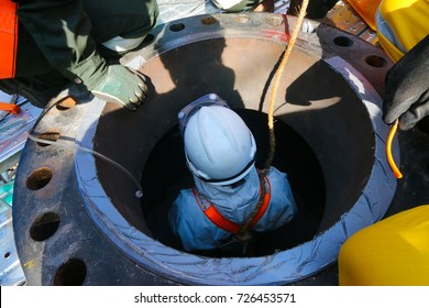 Confined Space Entry By A Worker Who Wear White Chemical Suit.