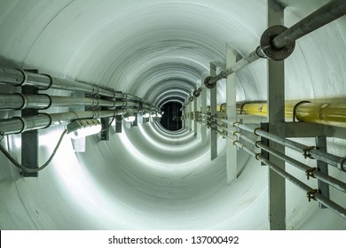 Confined space inside underground tunnel. Construction from engineering technology for infrastructure i.e. power line or cable, steel pipe in perspective view. To transport water, gas and electricity.