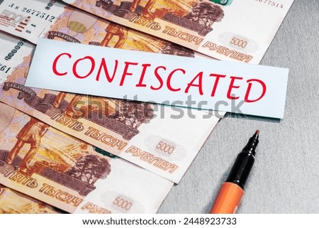 Confiscation of capital, rubles money concept.   Ruble banknotes and list with CONFISCATED word.