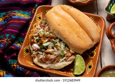 Confit pork sandwich called Torta de carnitas on white background. Traditional Mexican food