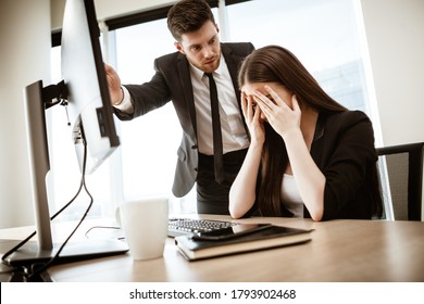 Conflict, Crisis And Dismissal At Work. Young Businessman Yells At Subordinate Female Assistant After Her Failure. Businessman Points At Monitor And Fires Worker. Resolving A Serious Work Problem