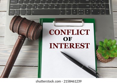 CONFLICT Of INTEREST - Words On A White Sheet On The Background Of A Laptop, A Court Hammer And A Pen. Business Concept