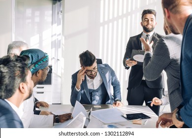 Conflict On Business Meeting With Team. Young Male Chief Executive Feeling Tired, Stressed And Exhausted During Stressful Business Negotiations With International Partners.