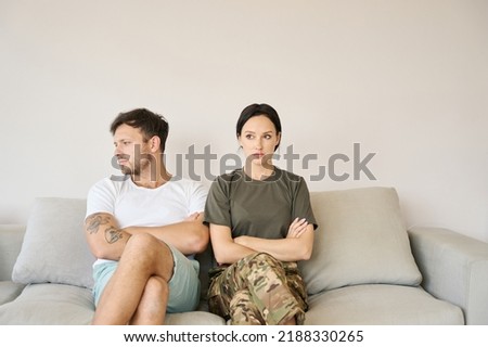 Conflicting couple sitting on sofa in closed poses