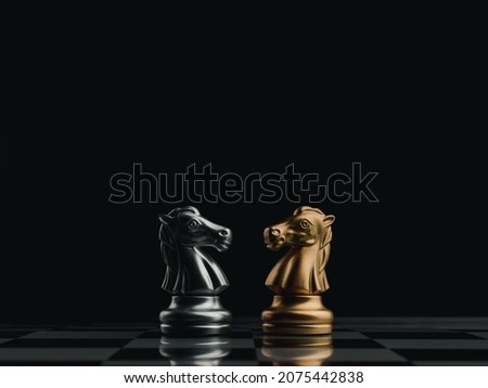 The confront between golden and silver horses, knight chess piece standing together on chessboard on dark background. Leadership, partnership, competitor, competition, and business strategy concept.