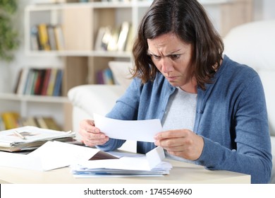 Confused Adult Woman Looking At Receipts Sitting In The Livingroom At Home