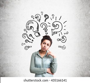 Confused African American Woman Trying To Find Answers To Her Questions With Question Mark Sketches On Concrete Background