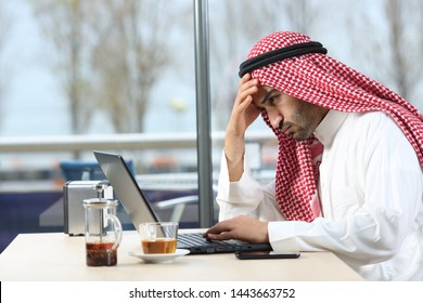 Confused Arab Man Checking Laptop Content Sitting In A Coffee Shop