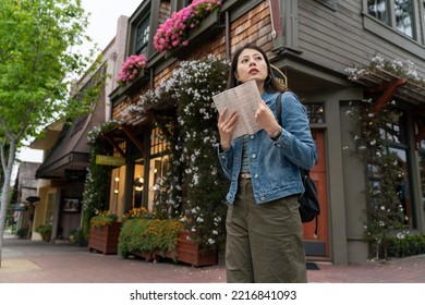 Confused Asian Taiwanese Girl Tourist Looking Around At The Street Corner In Carmel By The Sea With A Travel Guide Book In Hand. She Has No Idea Which Way To Go