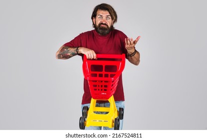 Confused bearded man with empty shopping cart. Male shopper in supermarket. Buying. Sale. Discount.