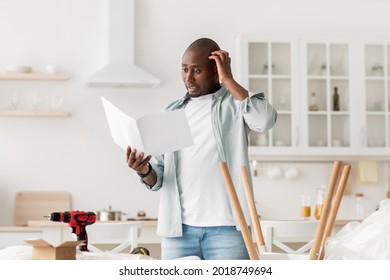 Confused black man having hard time assembling furniture and reading self-assembly manual, standing in kitchen interior, free space. Male struggling furnishing and installing furniture at home - Powered by Shutterstock