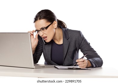 Confused Business Woman Working On A Laptop And Write In The Notebook