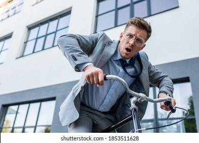 Confused Businessman Looking At Camera While Cycling Near Building