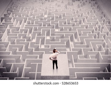 A confused businessman thinking while standing on a square platform above a detailed maze - Shutterstock ID 528653653