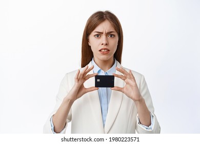 Confused Businesswoman In Suit Shows Plastic Credit Card, Look With Displeased Cringe Face, Standing Over White Background