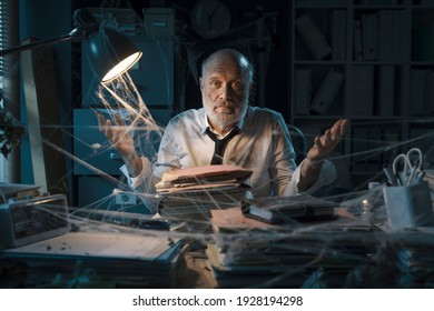 Confused Corporate Businessman Sitting At Desk In A Abandoned Dusty Office And Shrugging, Business Failure Concept