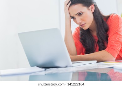 Confused designer looking at her laptop in a bright creative office