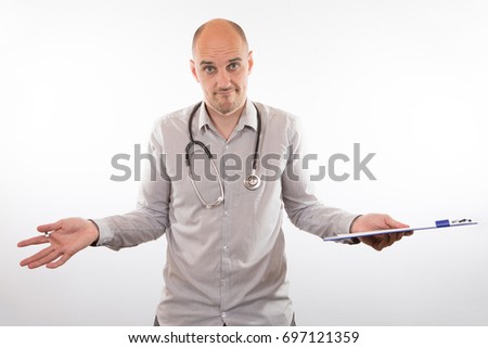 Confused doctor with a stethoscope round his neck holding a clipboard shrugging his shoulders to show his ignorance