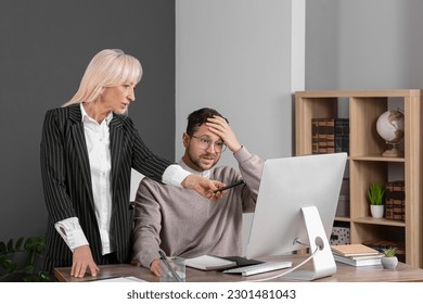 Confused employee and boss pointing at computer in office