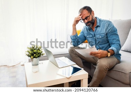 Confused frustrated mature man holding mail letter and money, reading shocking unexpected news nonsense in paper document, mad about high bill tax invoice, debt notification, money problem.