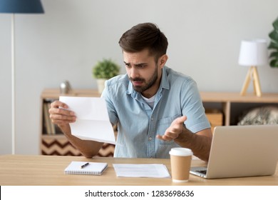 Confused frustrated young man holding mail letter reading shocking unexpected news nonsense in paper document, mad about high bill tax invoice, debt notification, bad financial report, money problem