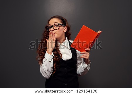 confused girl with book over dark background