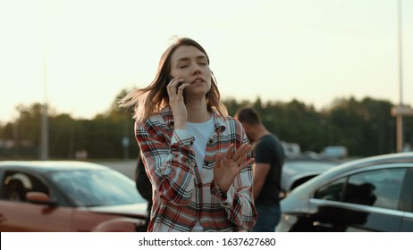 Confused Girl At Car Crash Using A Smartphone Calling For Help Standing With Miserable Expression Outdoors. Road Accident,. Police Investigation.