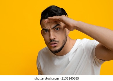 Confused Handsome Bearded Young Arab Guy Holding Hand By Forehead And Looking At Camera Over Yellow Studio Background, Feeling Suspicious, Cant Believe His Eyes, Copy Space