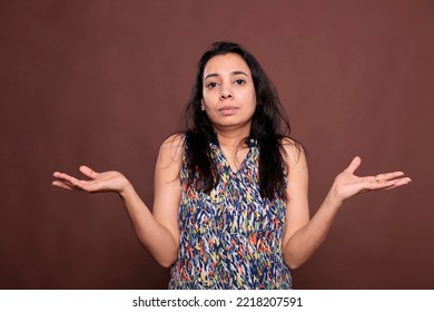 Confused Indian Woman Shrugging Shoulders With Questioning Facial Expression Portrait. Puzzled Lady Standing With Hands Spread Wide, Doubting, Pensive Person Looking At Camera