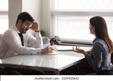 Confused male hr manager listening to female job applicant at interview. Young woman making bad first impression on doubtful company recruiter. Employer unsure about working experience of candidate.