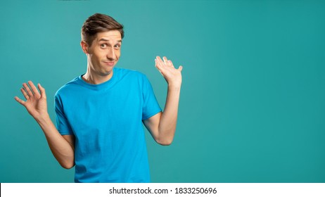 Confused Male Portrait. Refusal Gesture. So What. Clueless Emotion. Puzzled Expressive Man Raising Hands Saying It's Not Me Looking At Camera Isolated On Blue Copy Space.