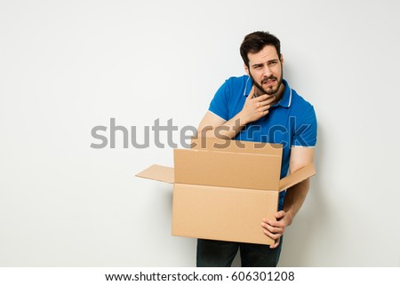 confused man looking for something in a carton box on a white wall