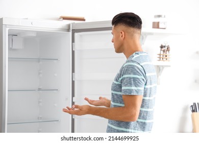 Confused Man Near Empty Fridge In Kitchen