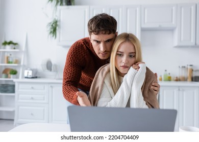 Confused Man In Sweater And Blonde Woman Looking At Laptop While Working From Home