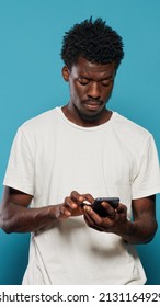 Confused Man Using Smartphone For Text Messages And Browsing Internet. Portrait Of Modern Person Looking At Mobile Phone With Touch Screen For Online Communication Feeling Disoriented.