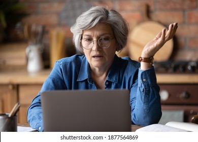 Confused Middle Aged 60s Woman In Glasses Looking At Computer Screen, Stressed Of Getting Message With Bad News. Unhappy Mature Lady Feeling Nervous About Bad Laptop Work Or Poor Internet Connection.