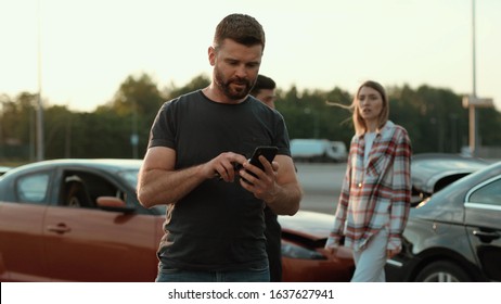 Confused Middle-aged Man In Trouble Using A Smartphone Outdoors. Male Driver Upset With The Situation. Car Crash. Police In Action.