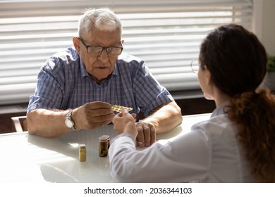 Confused Older 80s Male Patient Taking Pills From GP Doctor For Mental Health, Consulting About Dementia Therapy. Female Practitioner Prescribing Drugs, Medications To Senior Mature Man At Appointment